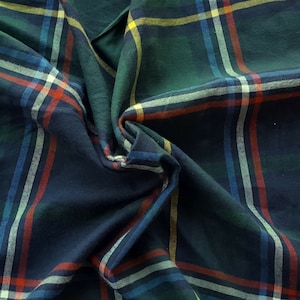 May include: A close-up of a blue, green, red, and white plaid fabric. The fabric is folded and wrinkled, showing the texture of the material.