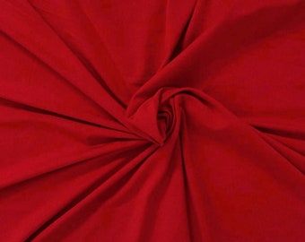 May include: A close-up of a smooth, red fabric with a soft, flowing texture. The fabric is folded and draped, creating a sense of movement and depth.