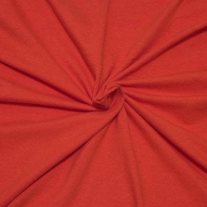 May include: A solid, vibrant red fabric featuring a soft, matte texture. The material is gathered in the center, creating natural, radiating folds and deep shadows that highlight the consistent, bold color across the entire surface of the textile.