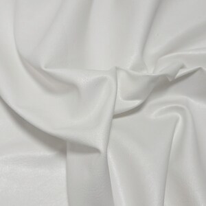 Pode incluir: Close-up de tecido branco com dobras suaves e textura sutil. O material parece liso e ligeiramente reflexivo, com sombras vari&aacute;veis que criam profundidade. Adequado para roupas ou decora&ccedil;&atilde;o de casa.