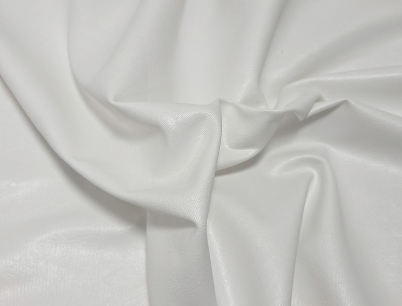 Pode incluir: Close-up de tecido branco com dobras suaves e textura sutil. O material parece liso e ligeiramente reflexivo, com sombras vari&aacute;veis que criam profundidade. Adequado para roupas ou decora&ccedil;&atilde;o de casa.
