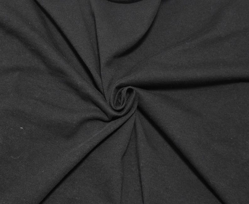 Puede incluir: Una tela negra s&oacute;lida con una textura suave y mate. El material est&aacute; recogido en el centro, creando pliegues suaves y radiantes y drapeados naturales que se extienden hacia los bordes del marco, mostrando el color oscuro y consistente.