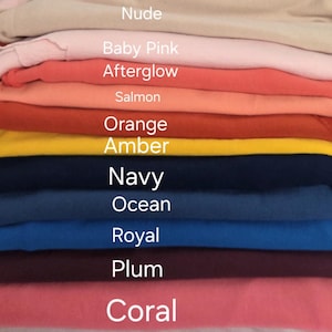 May include: A stack of folded fabric in various colors, including nude, baby pink, afterglow, salmon, orange, amber, navy, ocean, royal, plum, and coral. The names of the colors are displayed in white text.