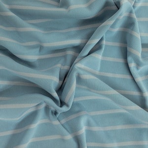 May include: A close-up of a blue and white striped fabric with a ribbed texture. The fabric is folded and creased, creating a soft and inviting look.