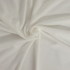 May include: White fabric with a smooth, silky texture. The fabric is folded and draped, creating soft folds and curves.