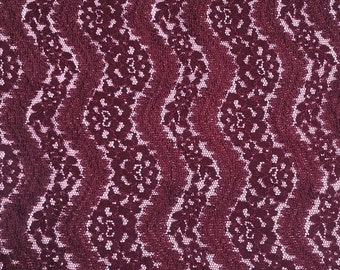 May include: Burgundy lace fabric with a wavy pattern. The lace has a delicate floral design.