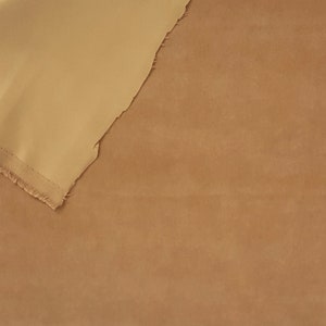 K&ouml;nnte beinhalten: Zwei Stoffst&uuml;cke, eines beige und eines in einem helleren Beigeton, liegen &uuml;bereinander. Das obere Stoffst&uuml;ck ist umgeklappt und das untere Stoffst&uuml;ck ist darunter sichtbar.