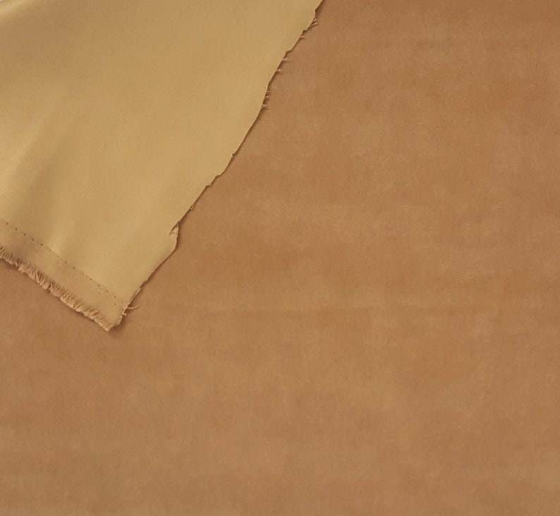 K&ouml;nnte beinhalten: Zwei Stoffst&uuml;cke, eines beige und eines in einem helleren Beigeton, liegen &uuml;bereinander. Das obere Stoffst&uuml;ck ist umgeklappt und das untere Stoffst&uuml;ck ist darunter sichtbar.