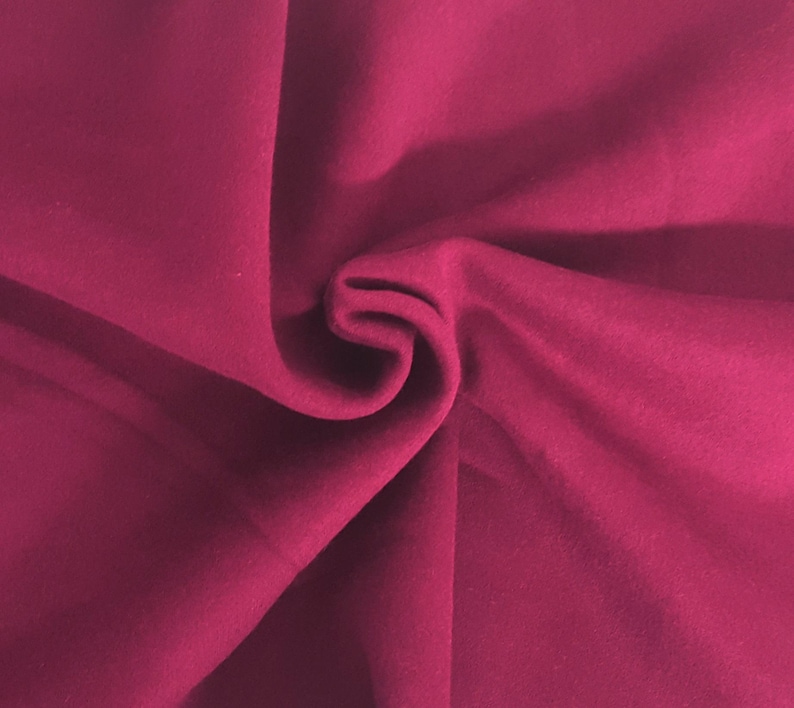 May include: A solid magenta fabric with a smooth, matte texture. The material is gathered in the center, creating soft, flowing folds and deep shadows that highlight the consistent, vibrant pinkish-red color across the entire surface.