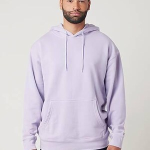 May include: A light purple hoodie with a front pocket and a drawstring hood. The hoodie is made of a soft material and is worn with blue jeans. The model is standing in front of a white background.