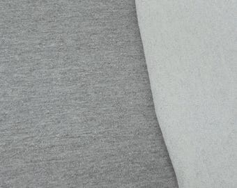 May include: Close-up of two fabric swatches. One is a heather gray knit fabric, and the other is a white, textured fabric. The fabrics are side by side, showing the contrast in texture and color.