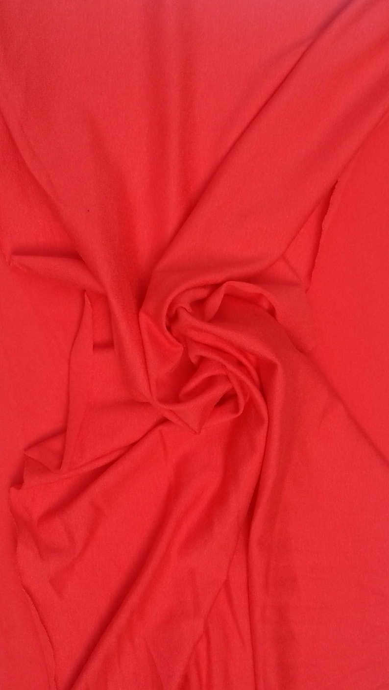 May include: A close-up of a bright red fabric, showing the texture and folds of the material.