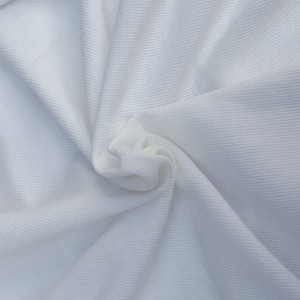 May include: White ribbed fabric with a soft, textured surface. The fabric is folded and draped, showing its texture and drape.