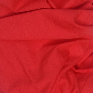 May include: A close-up of a smooth, red fabric with a soft, textured surface.