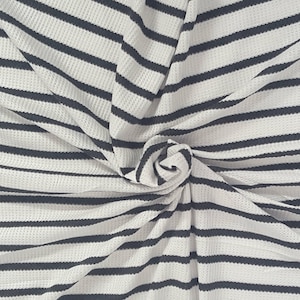 May include: White fabric with navy blue horizontal stripes. The fabric is textured and appears to be folded and twisted, creating a spiral effect in the center. The stripes are evenly spaced.