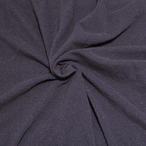 May include: Close-up of a dark navy blue fabric, tightly swirled to create a central focal point. The material has a textured appearance, with visible woven threads. The fabric's folds and shadows add depth and dimension.