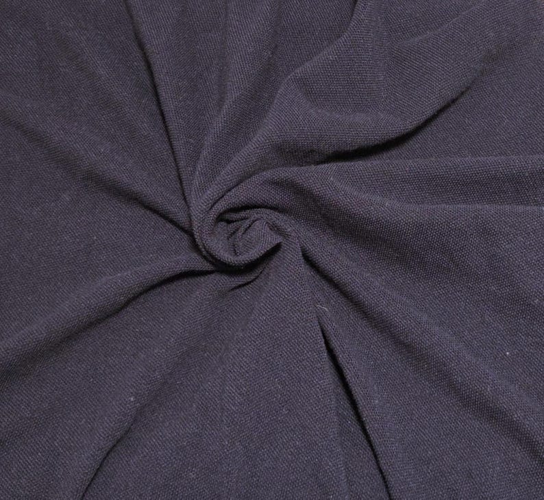 May include: Close-up of a dark navy blue fabric, tightly swirled to create a central focal point. The material has a textured appearance, with visible woven threads. The fabric's folds and shadows add depth and dimension.