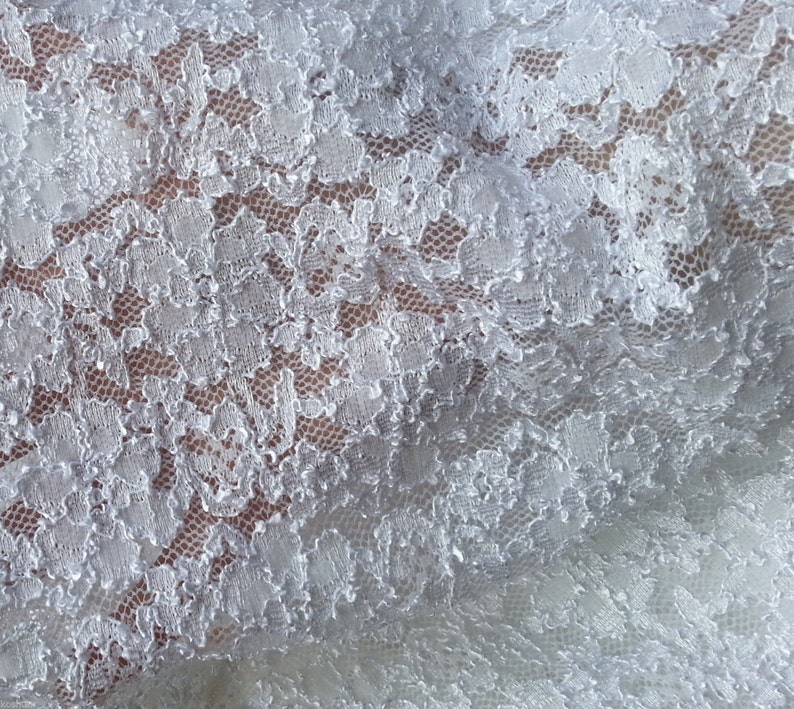 May include: White lace fabric with a delicate floral pattern. The lace is soft and flowing, with a subtle sheen.
