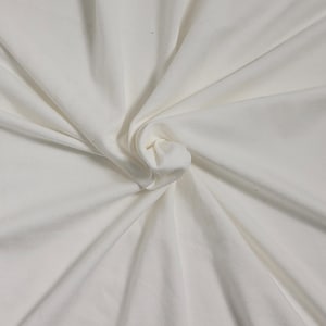 May include: A close-up of a white fabric with a smooth texture. The fabric is folded and twisted, creating a soft, flowing look.