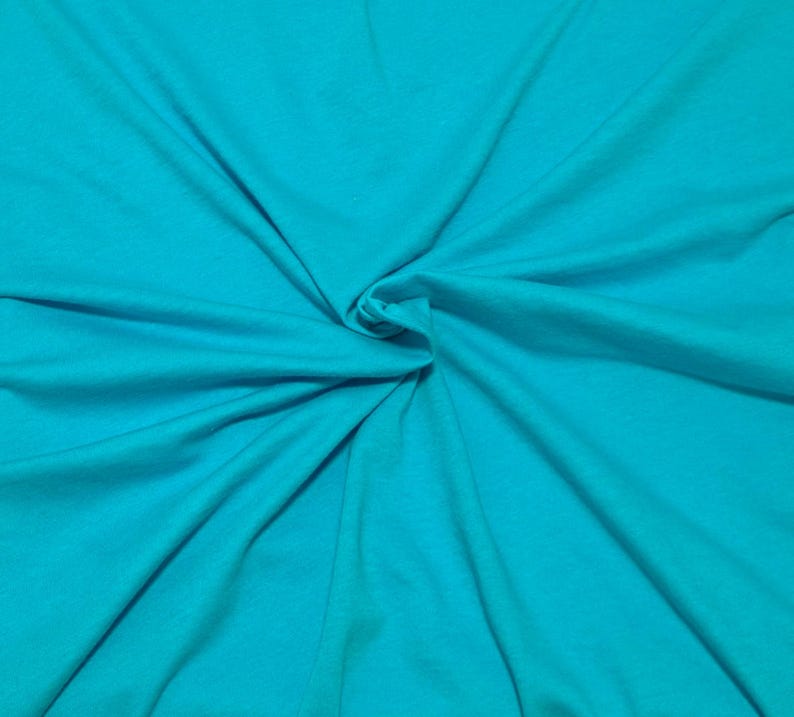 Puede incluir: Una tela de color turquesa s&oacute;lido con una textura suave y mate. El material est&aacute; recogido en el centro, creando pliegues naturales y radiantes junto con sombras suaves que se extienden hacia los bordes del marco, resaltando el color.