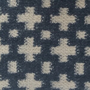 May include: A close-up of a textured fabric with a repeating pattern of white and dark blue shapes. The fabric has a fuzzy, soft texture.
