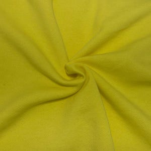 May include: A bright yellow fabric with a soft, matte texture. The material is gathered in the center, creating natural folds and radiating pleats that extend outward across the surface, showcasing the consistent, solid color of the textile.