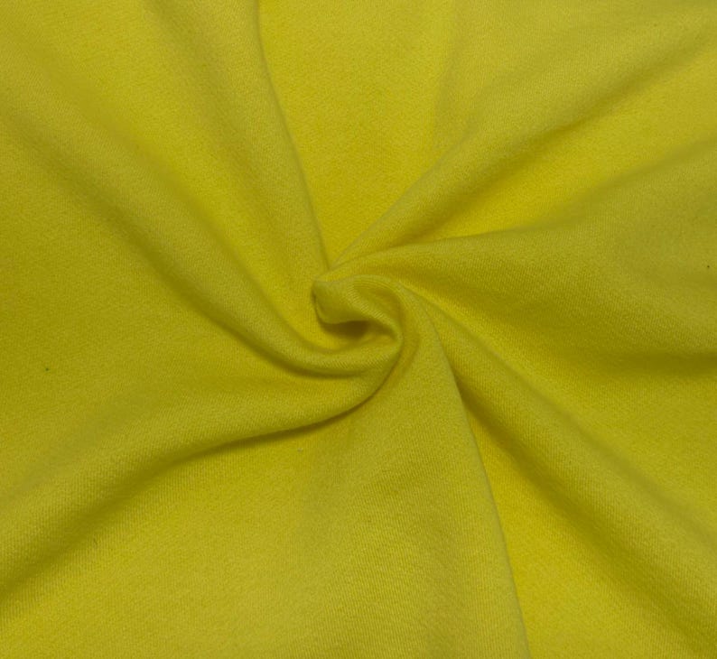 May include: A bright yellow fabric with a soft, matte texture. The material is gathered in the center, creating natural folds and radiating pleats that extend outward across the surface, showcasing the consistent, solid color of the textile.