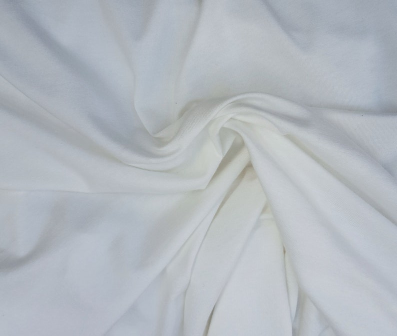 May include: White fabric with a smooth, soft texture. The fabric is folded and draped, creating a flowing, elegant look.
