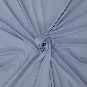 May include: A close-up of a light blue fabric with a soft, smooth texture. The fabric is draped and folded, creating a swirling pattern.