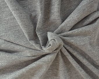 May include: Close-up of a gray fabric with a textured surface. The fabric is twisted and folded, creating a swirling pattern.