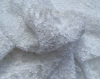 May include: White lace fabric with a delicate floral pattern. The fabric is soft and flowing, and it would be perfect for a variety of projects, such as wedding dresses, tablecloths, and curtains.