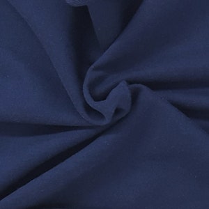 May include: Close-up of navy blue fabric with soft folds and a matte finish. The material appears to be a medium-weight textile, suitable for apparel or home decor projects. The deep blue color is consistent throughout the fabric.