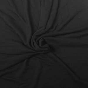 May include: Black fabric with a soft, smooth texture. The fabric is draped and folded, creating a swirling pattern.