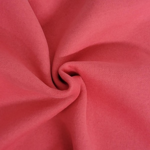 May include: A solid, deep rose-pink fabric with a soft, matte texture. The material is gathered in the center, creating natural folds and shadows that highlight the consistent, uniform color and the smooth, non-reflective surface of the textile.