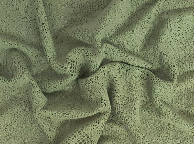 May include: A close-up of a sage green crocheted fabric with a textured, open-weave pattern.