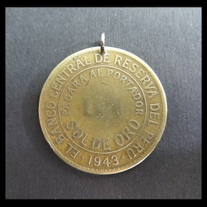 Könnte beinhalten: Ein goldfarbener Münzanhänger mit Öse zum Aufhängen. Die Münze trägt spanische Inschriften, darunter "BANCO CENTRAL DE RESERVA DEL PERU" und "SOL DE ORO 1943". Es ist ein Vintage-Sammlerstück.