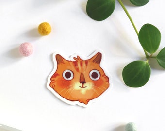 Autocollant avec une illustration d'une tête de chat roux qui sourit