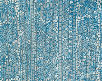 May include: A blue and white fabric with a repeating floral pattern. The fabric has a textured, woven look.