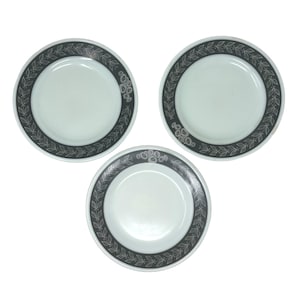 May include: Three white ceramic plates with a black and white floral border. The plates are all the same size and have a simple design.