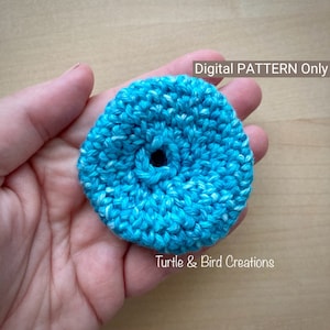 May include: A close-up of a crocheted blue and white circle with a hole in the centre. The circle is being held in a hand. The text "Digital PATTERN Only" and "Turtle & Bird Creations" is visible in the image.