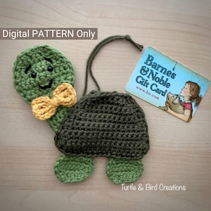 May include: Crocheted green turtle with a yellow bow tie. The turtle has a smiling face with black eyes. The turtle is holding a gift card for Barnes & Noble.