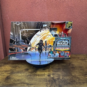 May include: A Star Wars "The Death Star" action playset in its original packaging. The box features a scene with a black-suited character and various spacecraft. The packaging includes the Star Wars logo and the text "The Death Star".