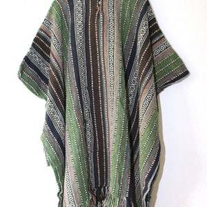 May include: A hooded poncho featuring a vertical striped pattern in shades of forest green, dark brown, black, and beige. The garment includes a front placket with two wooden toggle buttons at the neckline and a fringed hem along the bottom edge.