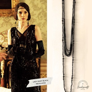 Puede incluir: Un conjunto de 12 collares de cuentas negras. Los collares est&aacute;n superpuestos y presentan un dise&ntilde;o cl&aacute;sico. El texto "Lady Mary Black Necklaces" y "12 Necklaces Included" es visible en la imagen.