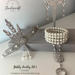 May include: Gatsby Jewelry Set 3 includes a silver headband with pearl accents, a pearl bracelet, and a pair of pearl drop earrings.