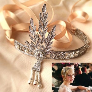 May include: A silver headband with a delicate floral design and pearl accents. The headband is adorned with sparkling rhinestones and features a dangling pearl and rhinestone drop.