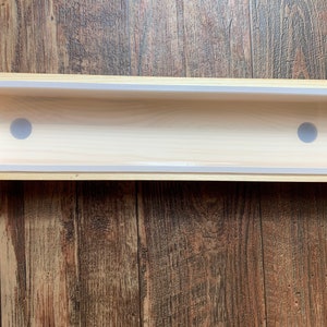 Puede incluir: Un molde de jab&oacute;n de madera con un inserto de silicona blanco. El molde tiene dos agujeros redondos en el inserto de silicona.