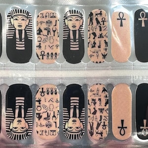 Op de afbeelding: Set van 10 nagelwraps met een Egyptisch thema. De wraps bevatten afbeeldingen van farao's, hiërogliefen en een ankh-symbool. De wraps zijn ontworpen om op vingernagels te worden aangebracht.