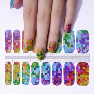 May include: A set of colorful nail wraps with a mosaic design. The wraps feature a glittery finish and a pattern of small squares in shades of yellow, green, blue, purple, and red. The nail wraps are shown on a white surface.