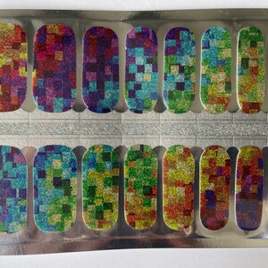 May include: Nail polish strips with a colorful, glittery mosaic pattern. The strips are arranged in a silver package, featuring a variety of colors including red, green, blue, and purple. The design is made up of small squares.